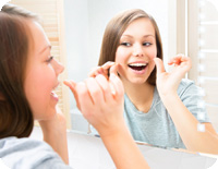 Beauty young woman flossing her teeth at home. Pretty teenage gi